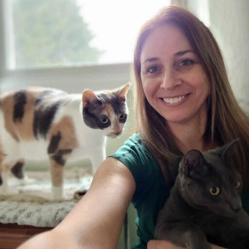 Christine Calnin smiling with two cats